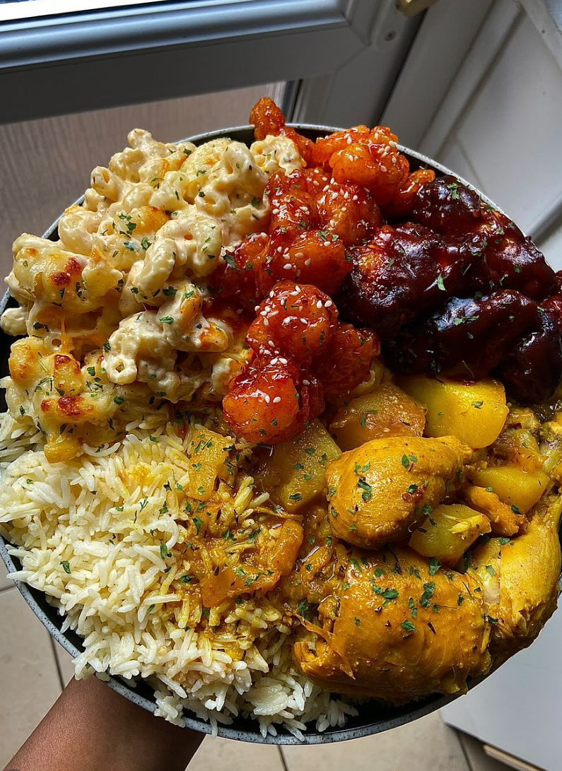 Loaded food bowl with mac and cheese, saucy wings, curry chicken and rice