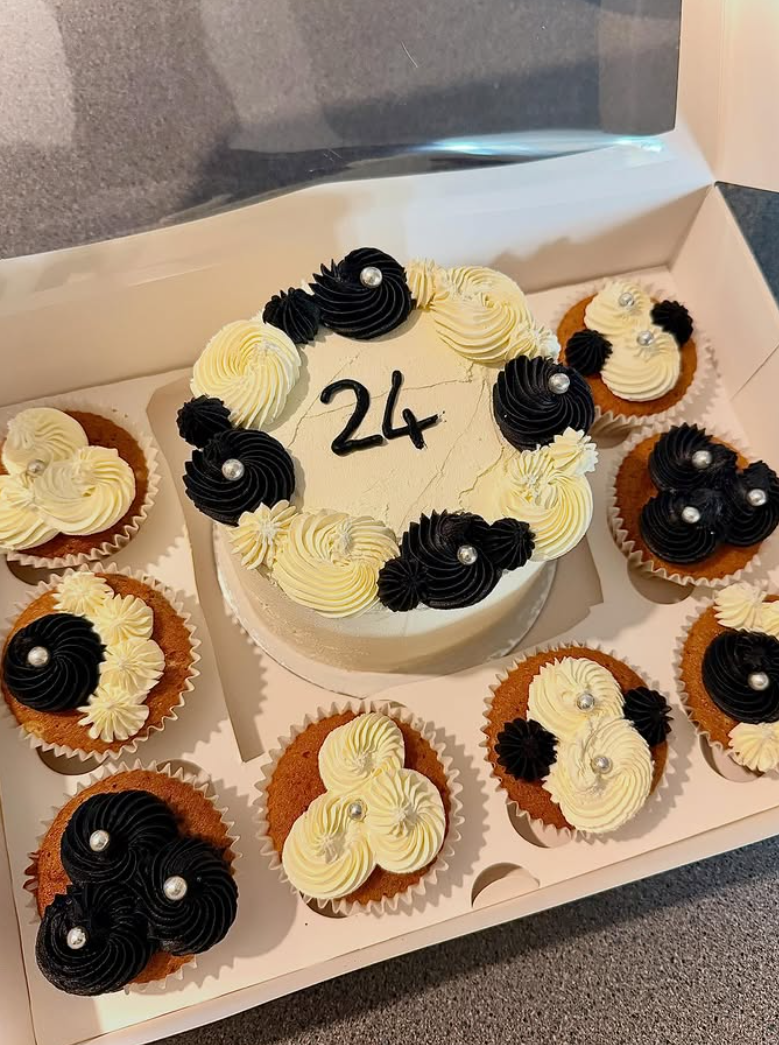 Black and cream birthday cake with matching cupcakes in a gift box